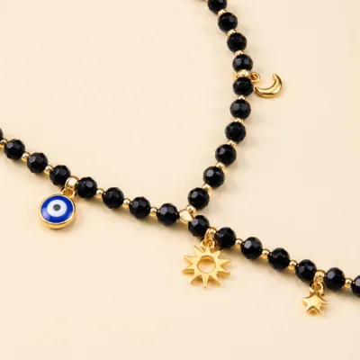 Pormenor dourado do colar de contas pretas com amuleto de olho azul