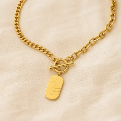 Colar dourado com medalhão de olho sobre tecido claro