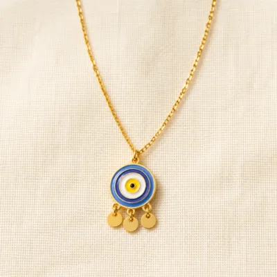 Colar dourado de olho azul sobre tecido claro